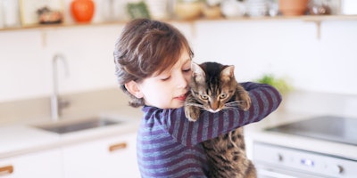 young boy holding cat in kitchen