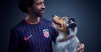 Person wearing Team USA soccer jersey with Australian Shepard dog