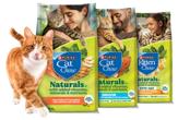 An orange and white cat rubs up against bags of Cat Chow Naturals