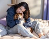 Person embracing dog on bed.