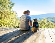 Person sitting with a service dog outdoors.