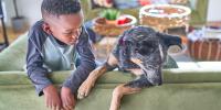 young boy lounging on a couch with a black and tan dog