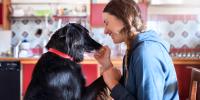 Mujer sonriendo cara a cara con un perro