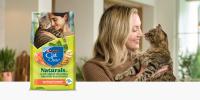 woman smiling and looking at tabby cat in her arms