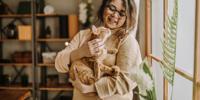 Person holding an orange tabby cat indoors near a sunlit window
