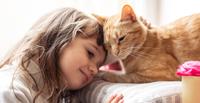 Young girl snuggling an orange tabby cat