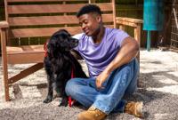 Man sitting on ground with black dog