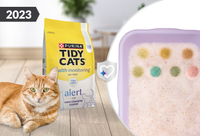 Cat laying by Tidy Cats Alert litter with color-changing crystal examples in litter box.