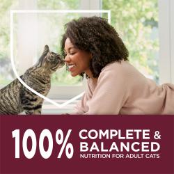 Una mujer sonríe mientras se sienta nariz a nariz con su gato. Un banner color burdeos muestra un texto que dice "100% nutrición completa y equilibrada para gatos adultos"