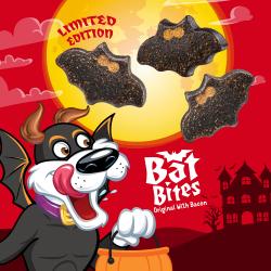 Three bat shaped Purina Beggin Bat Bites dog treats flying above Hamlet, the Beggin mascot, wearing a bat costume.