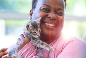 woman snuggling a small kitten and smiling