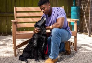 Hombre arrodillado en el suelo con un perro negro