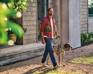A man walks his dog with him to recycle an empty bag of Purina Pro Plan dry dog food.