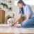 woman putting food out on a plate on the floor for her cat.