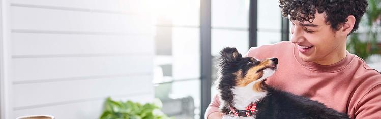 A human smiling down at their puppy looking back up at them