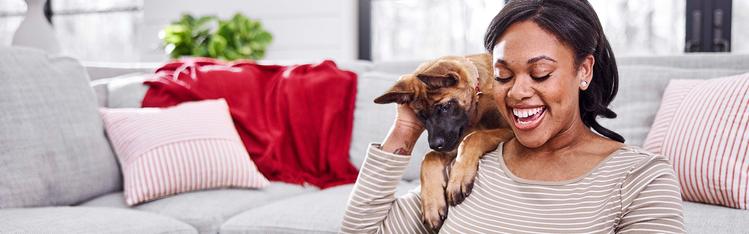 A human petting their puppy that is hanging over their shoulder.