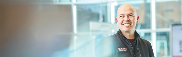Dr. Miles posing in a black jacket with a Purina logo