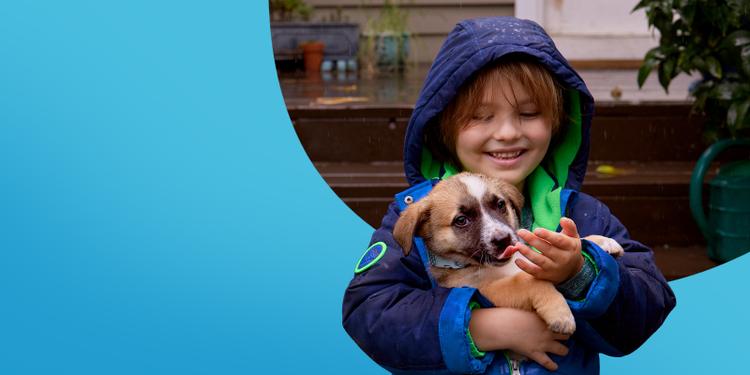 Child in rain coat holding a puppy
