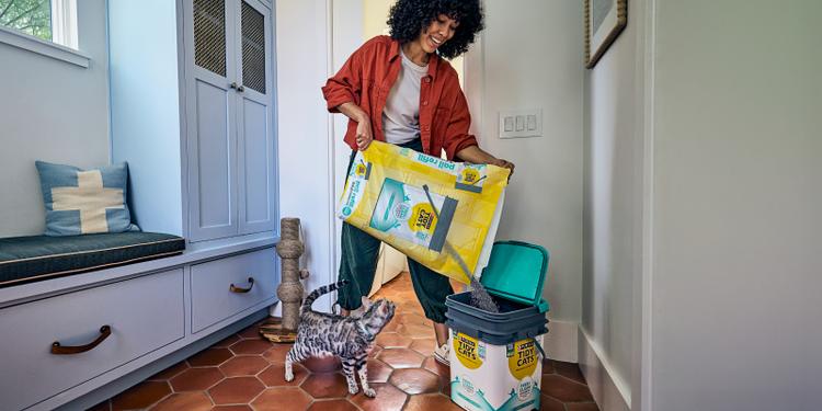 A woman pours a Tidy Cats litter refill bag into her previously used Tidy Cats plastic litter pail.