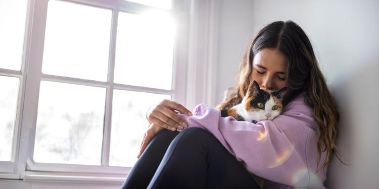 Girl in purple shirt snuggling cat