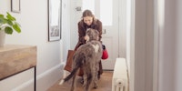 Una mujer caminando hacia la puerta acariciando a un perro que tiene ansiedad por separación