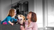 Mother and daughter smiling over golden retriever