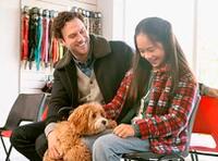 father and daughter smiling petting brown furry doodle dog