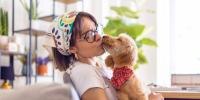 Woman kisses puppy while holding it in her lap