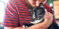 hombre acurrucándose con su gato blanco y negro