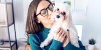 A woman holds her small dog with wet eyes close