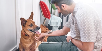 man smiling while petting a tan colored dog