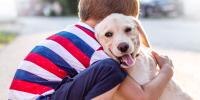 Un niño pequeño abrazando a un cachorro sonriente