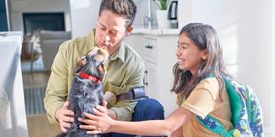 man and young girl petting a small black and tan dog