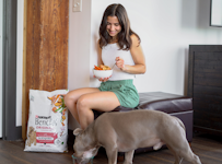 Influencer Grace Frisella and her dog each eating a bowl of food.