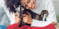 una mujer abrazando a su gato de color negro y marrón