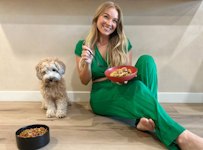 Influencer Alix Traeger sitting next to her dog, each with a bowl of food.