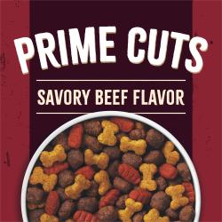 A close-up of a bowl of kibble sits on a maroon and brick red background. Text reads "Prime Cuts Savory Beef Flavor"
