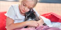 A young child cuddling with her cat