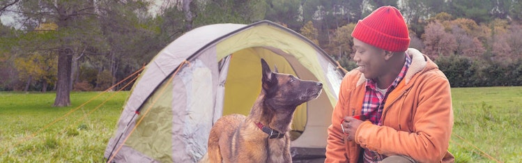 man with dog in front of tent