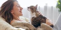 Woman smiling and cuddling with a long-haired tri-colored cat
