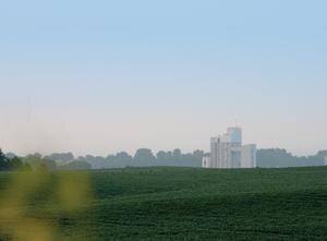 image of farm field with grain silo in the background