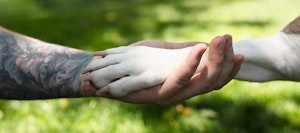 human hand holding dog paw