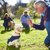 person kneeling in grass training golden retriever service dog puppy