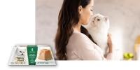 woman holding white cat with Fancy Feast Gems packaging in front of image