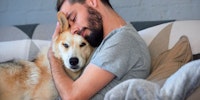 man hugging dog on couch