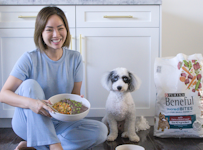 Influencer Joanna Park sitting next to her dog, each with a bowl of food.