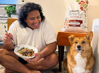 Influencer Ovi Kabir holding a bowl of food and sitting next to his dog.