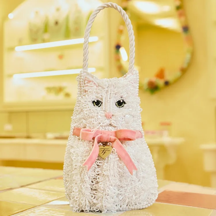 White beaded cat-shaped micro bag with a pink ribbon bow, featured as the Fancy Feast Little Gem sweepstakes prize.